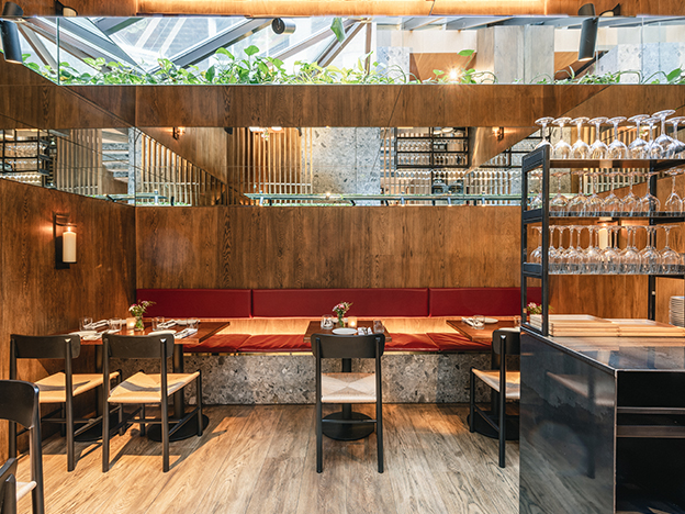 Contemporary gastro bar interior design with cast-iron shelving and open kitchen London.