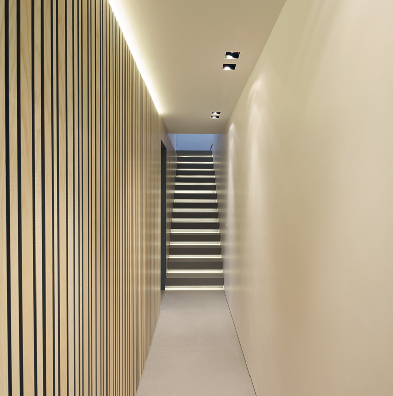 Modern minimalist hallway with an illuminated staircase.