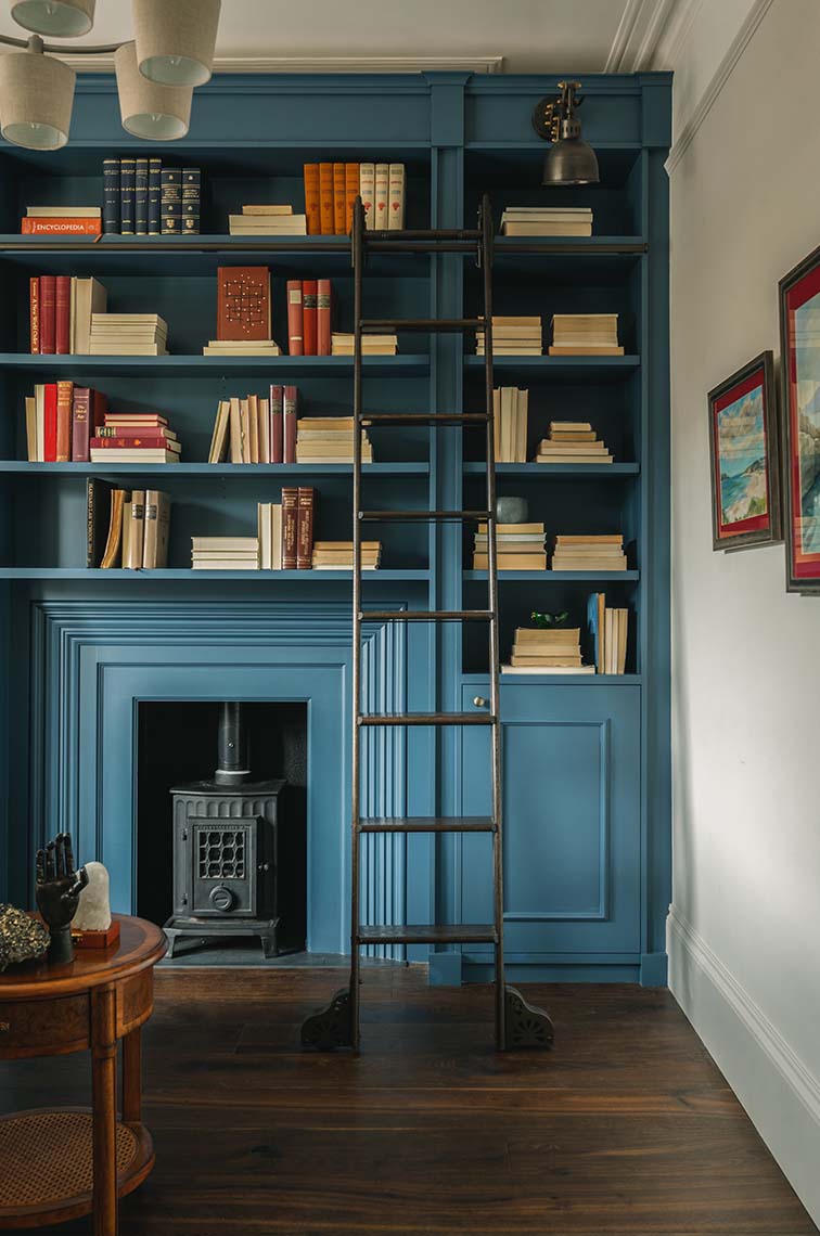 Modern eclectic study with a blue library with built-in bookshelves and ladder.