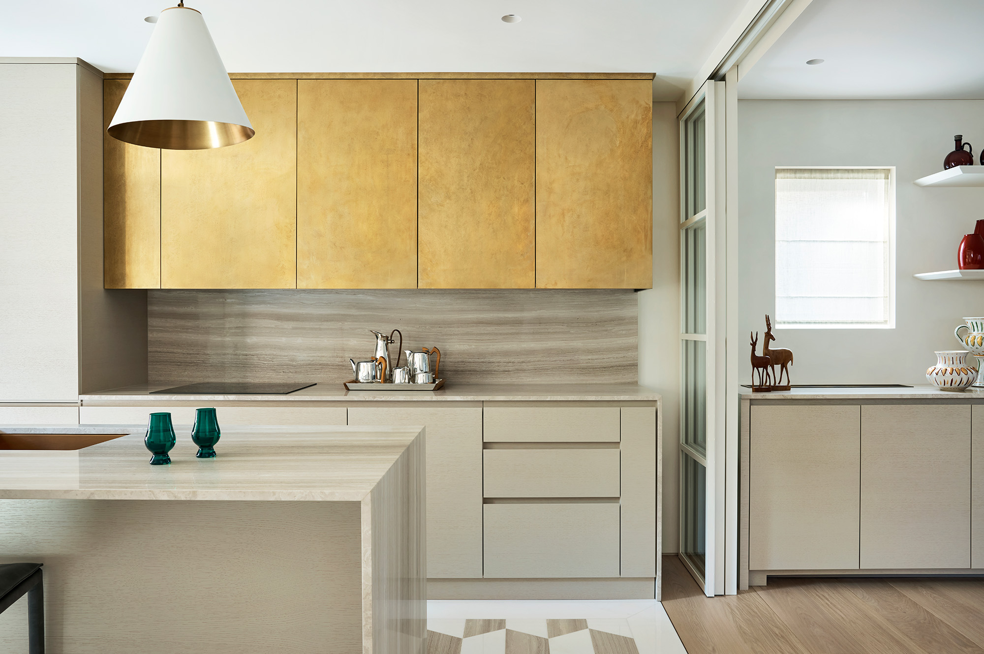 Bespoke open plan kitchen with silver travertine cabinetry and brass finishes.