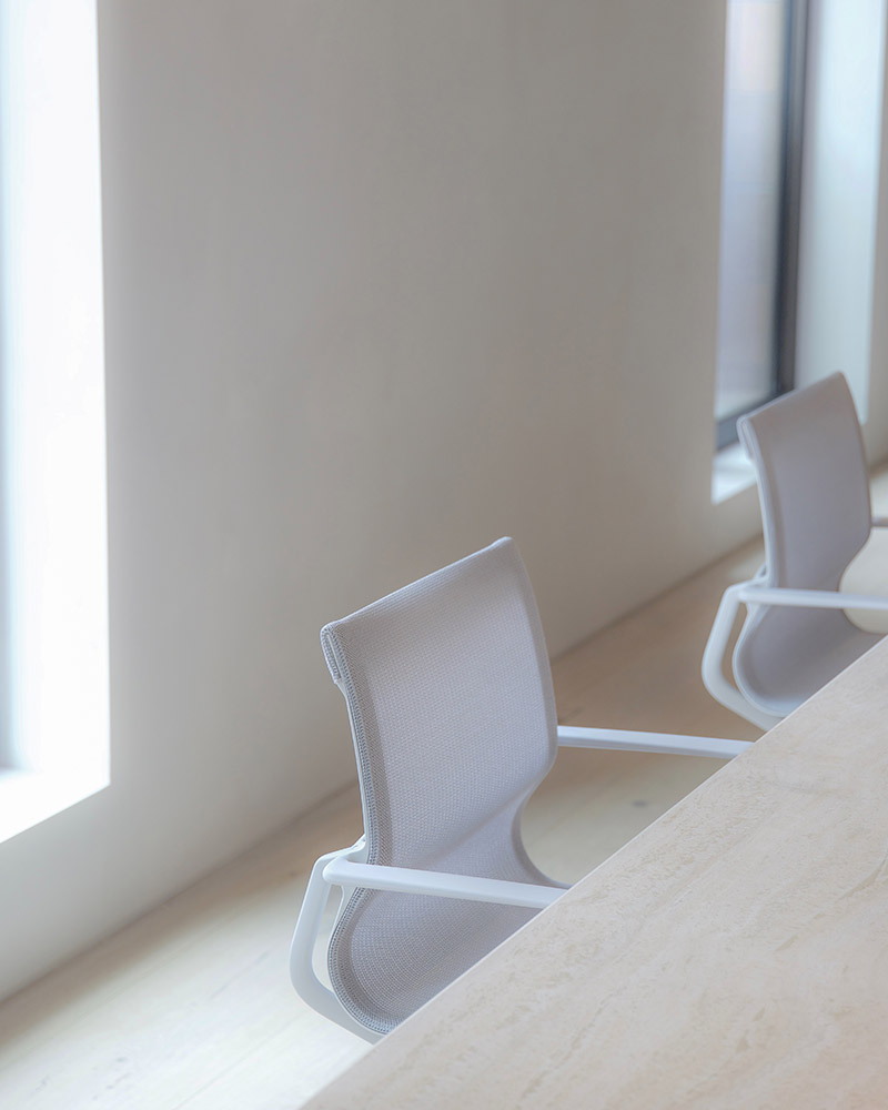 Bespoke solid limestone co-working station with white office chairs.